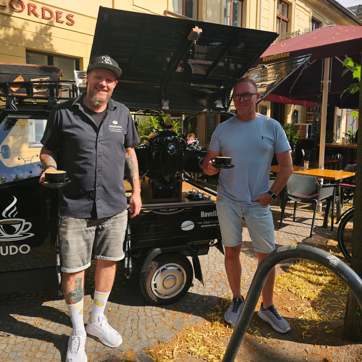 Barista und Gast mit Kaffeetassen vor der mobilen Kaffee Ape vor der Havelbohne in Potsdam